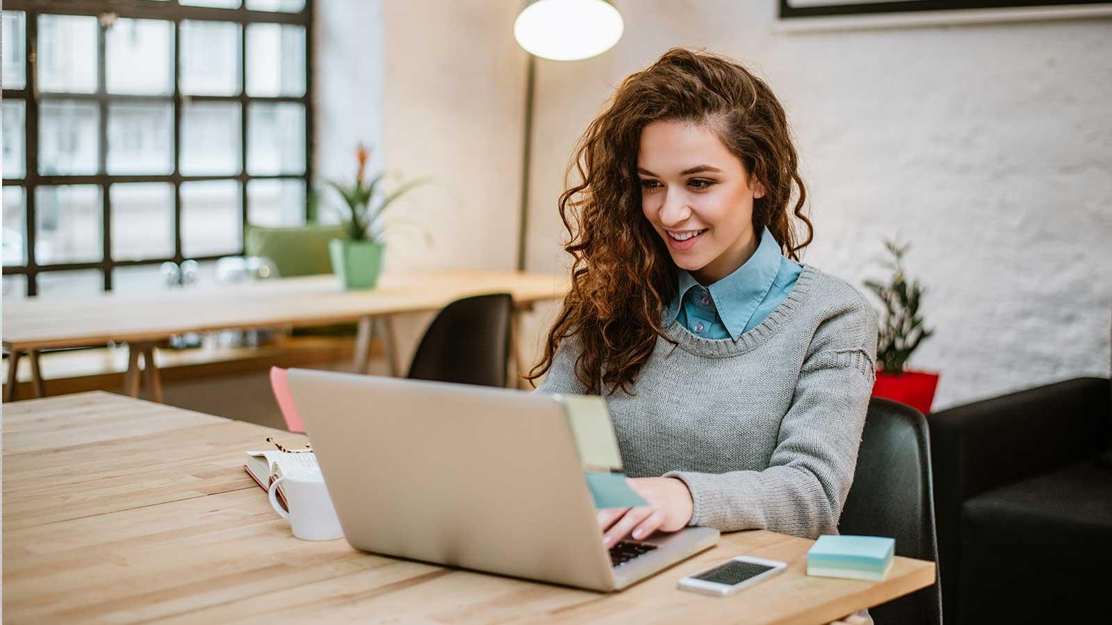 Woman working at a laptop and smiling