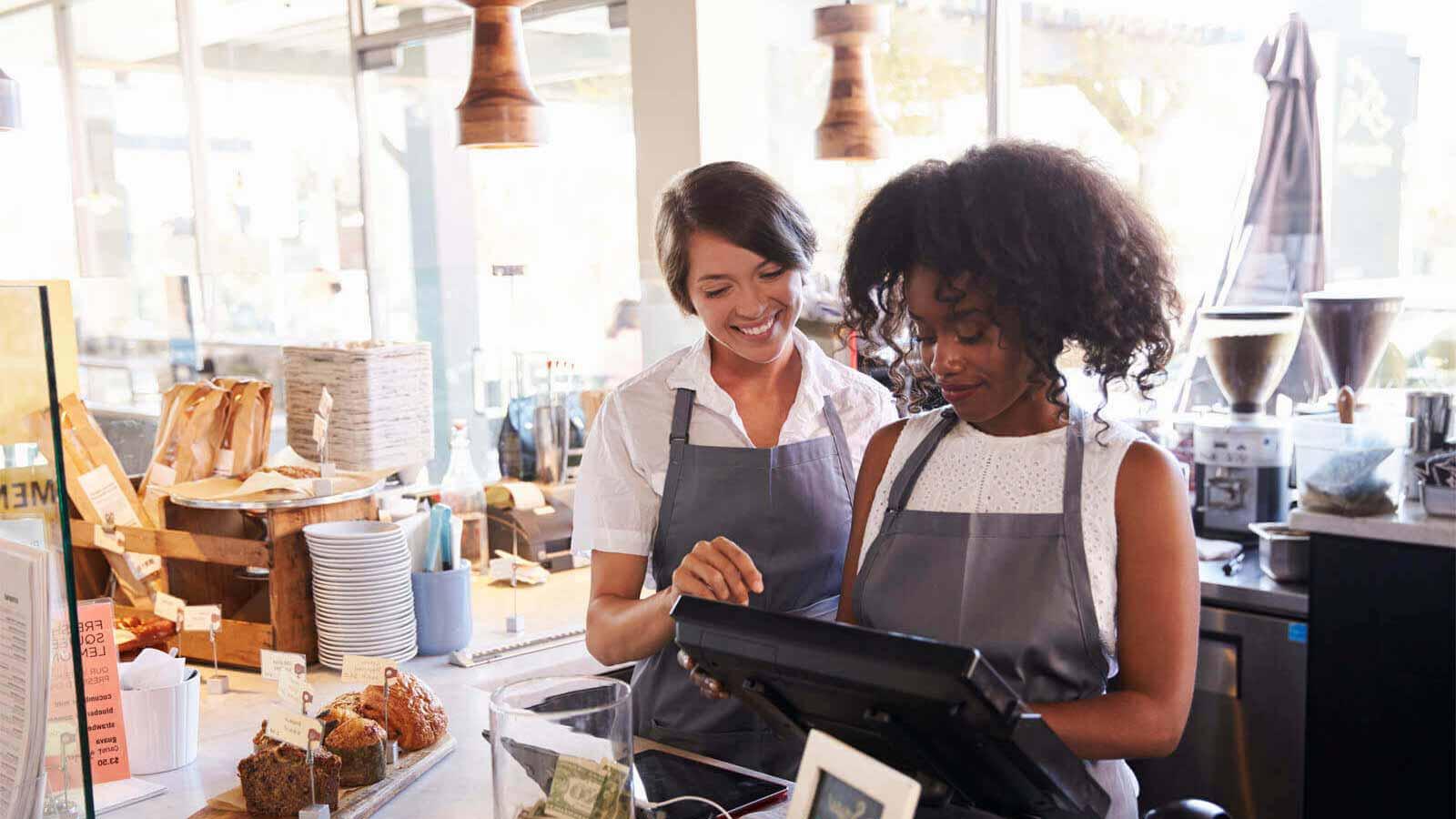 Two women working at the till of a coffee shop