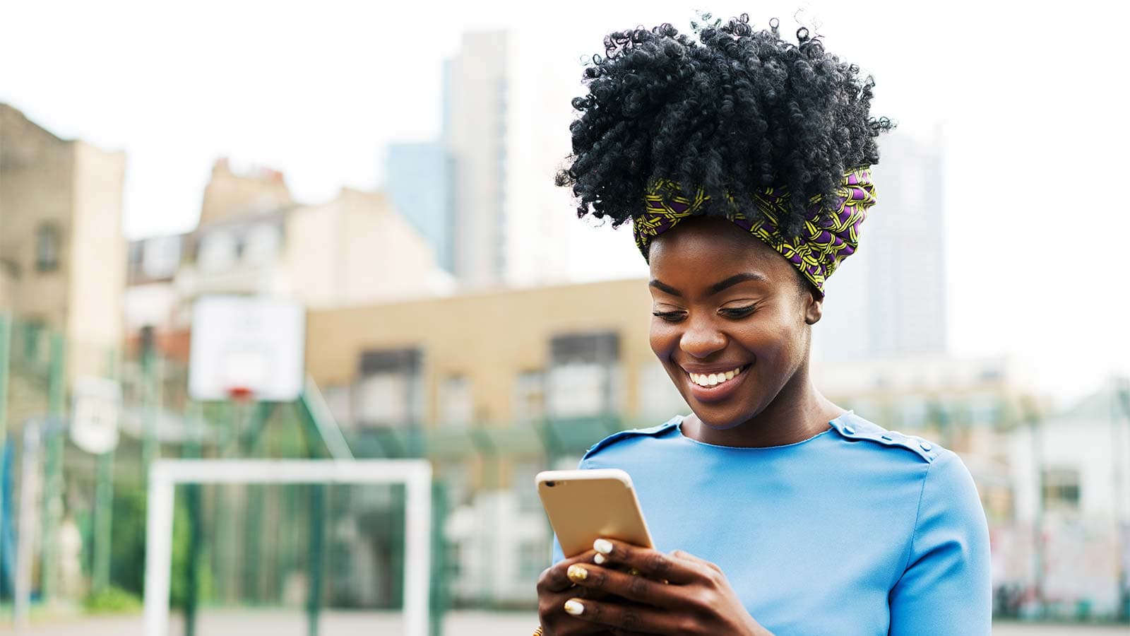 Young woman outside smiling and holding a mobile phone