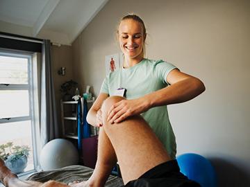 A patient lying down having physio on the knee area