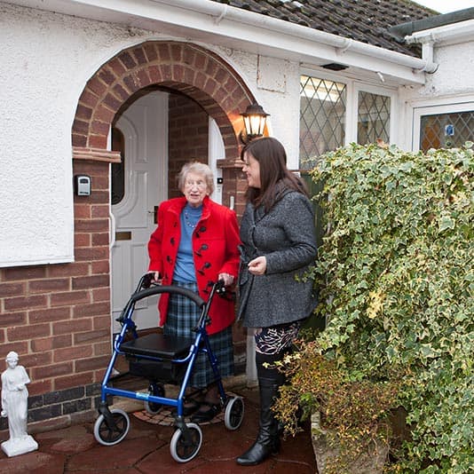 Woman helping elderly lady with stroller