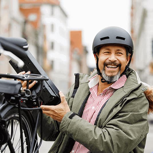 Man smiling and holding an electric bicycle