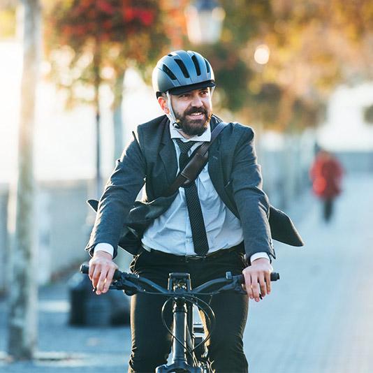 A man wearing a business suit and helmet riding on a bike