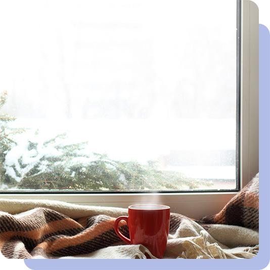 A hot drink in a mug, by a window with blankets