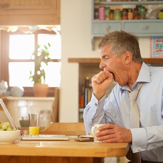 Man yawning at laptop