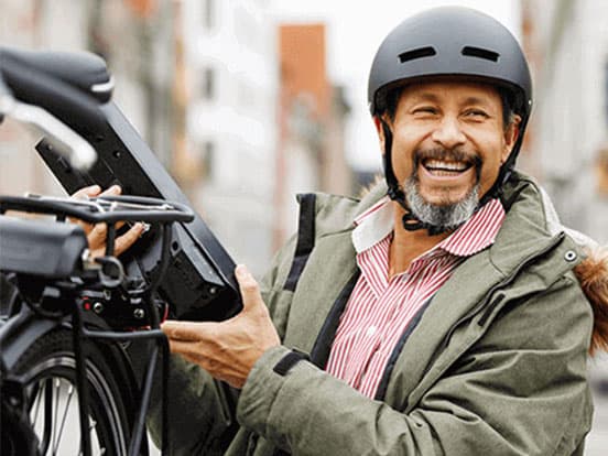 Man wearing a helmet and holding an electric bike