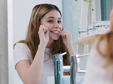 Woman flossing in front of the mirror