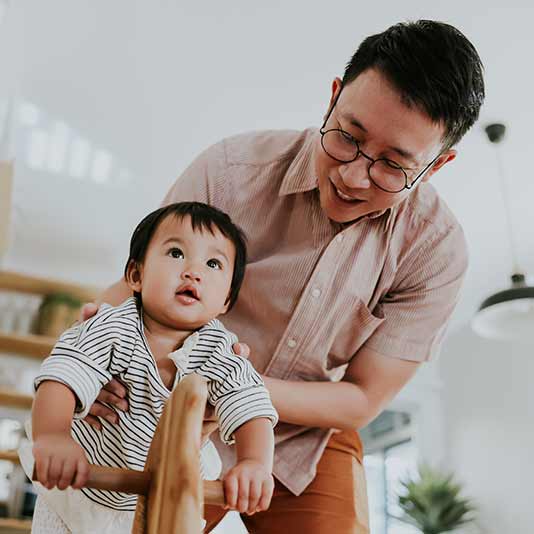 Father holding son on a rocking horse