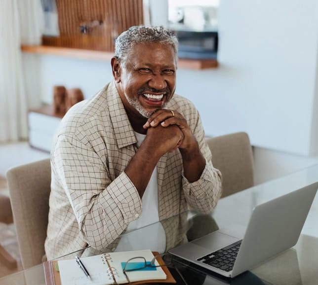 Man smiling while using laptop at home